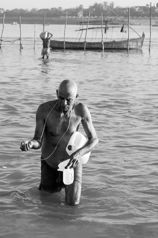 The connection between Water and Religion - pilgrim obtaining sacred water at the confluence of rivers Ganga, Yamuna and Sarasvati at Prayag (Allahabad), Uttar Pradesh